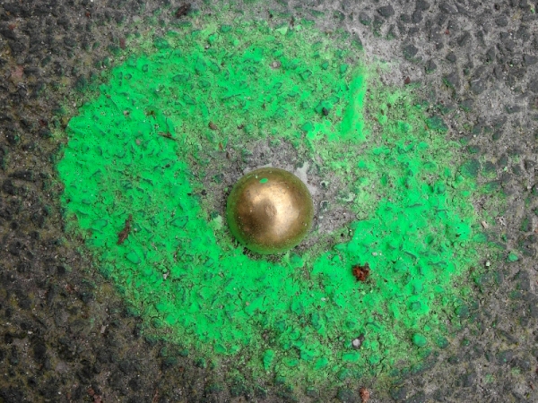 grün markierter Nagel im Asphalt